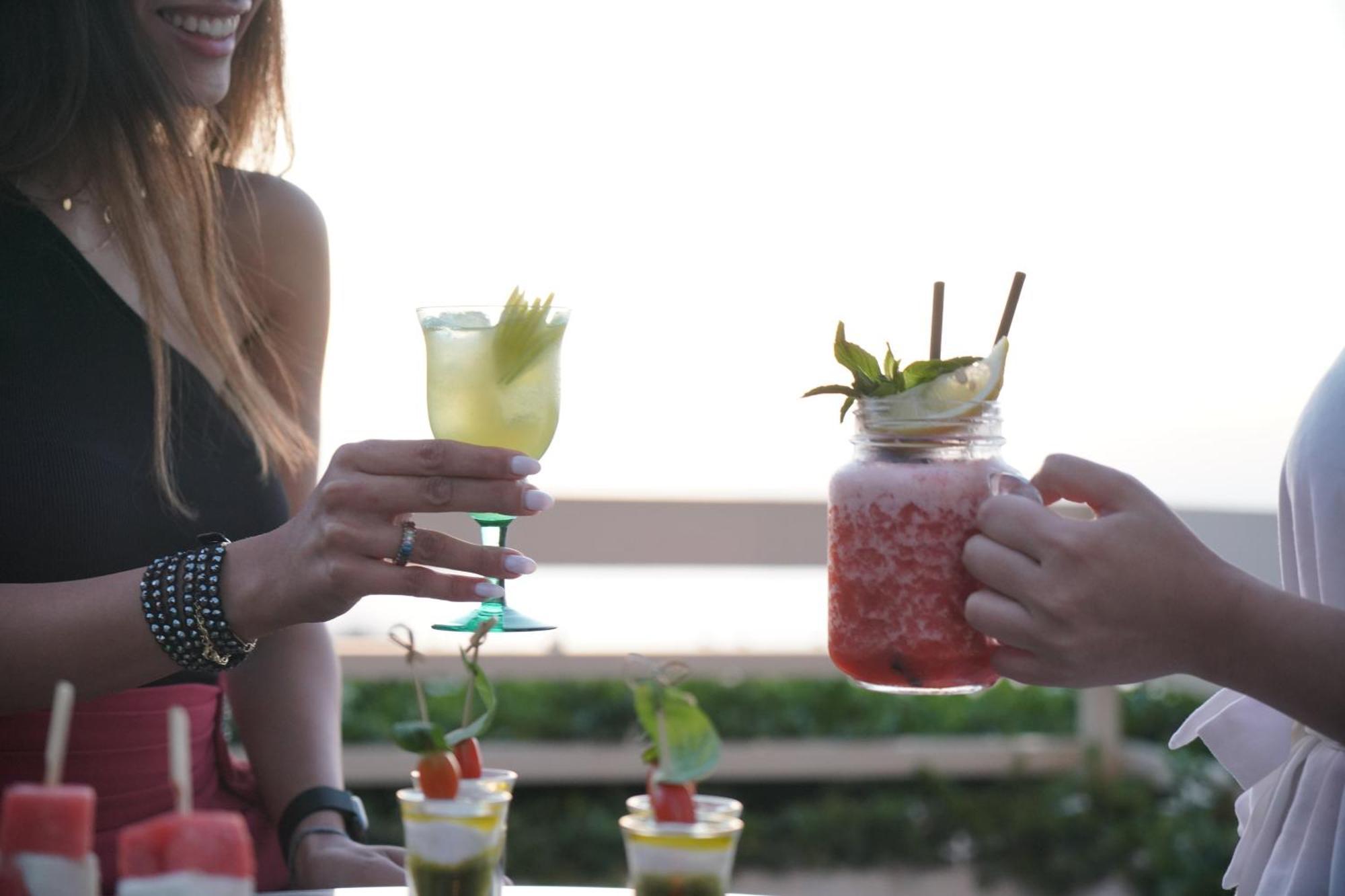 ホテル ゲフィノア ロターナ ベイルート エクステリア 写真 Two people holding cocktails